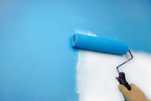 תהליך שיפוצים יד של אדם צובעת קיר, בררו על מחיר צביעה לדירה 4 חדרים